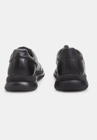Pantofi sport negri cu un upper din piele netedă, formă rotundă, guler căptușit și talpă din cauciuc texturat pentru aderență.
