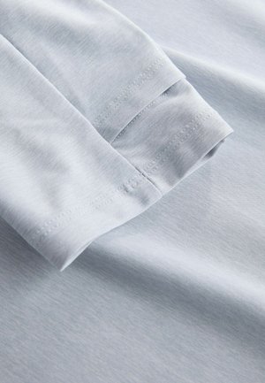 Hele sinine pikkade varrukatega rõiva varruka detail, mis näitab kangasteksti ja topeltõmmeldud servade kvaliteeti pehmel puuvillamaterjalil.