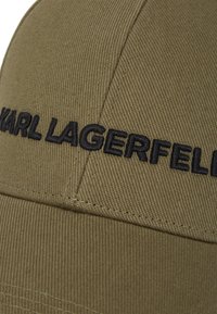 Olijfgroen baseballcap van textuurstof met zwart geborduurd "KARL LAGERFELD" logo aan de voorkant en gestikte naaddetails.