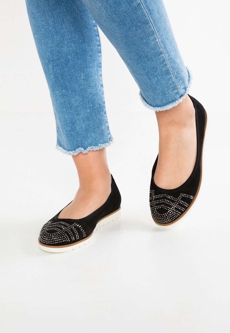 Sorte ruskind ballerinaer med et dekorativt mønster af sølvnitter, med en rund tå og en hvid gummisål. Båret med cropped denim.