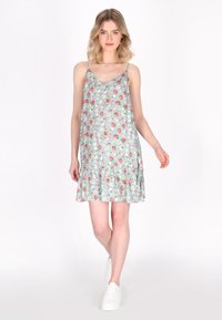 Abito floreale azzurro chiaro con spalline sottili e orlo a volant, decorato con fragole rosa e piccoli fiori bianchi su un tessuto morbido.