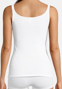 White cotton tank top with thin straps, smooth texture, and a fitted design, extending to the hips, shown from the back.