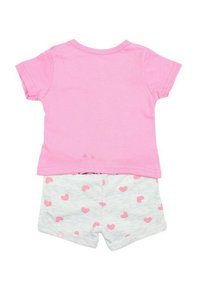 T-shirt en coton rose à manches courtes associé à un short gris clair avec de petits motifs de cœurs roses. Design simple et décontracté, idéal pour les enfants.