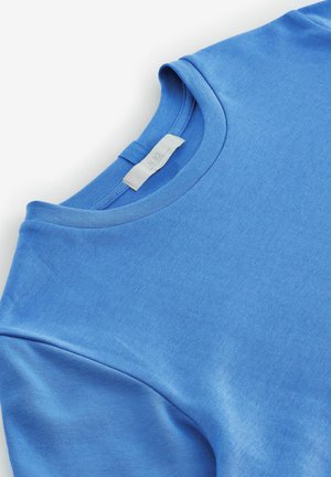 Blauer Baumwollpullover mit Rundhalsausschnitt, weicher Textur, flachen Nähten und einem Etikett mit der Aufschrift "N.82", das am Ausschnitt sichtbar ist.