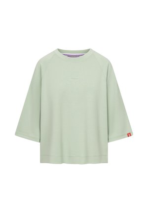 Luźna koszula w jasnozielonym kolorze z krótkim rękawem, okrągłym dekoltem i małym napisem „Frieda” na środku klatki piersiowej.