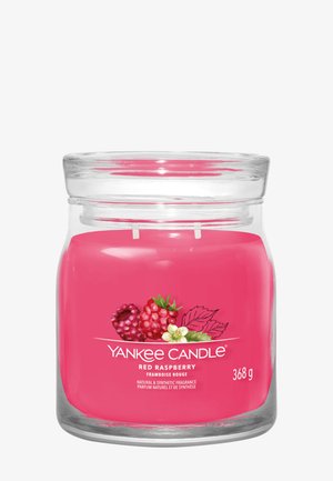 Doorzichtige glazen pot met helderroze geurkaars met de geur van rode framboos en een etiket met frambozen en groene bladeren, met een gewicht van 368 gram.