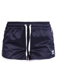 Námořnické modré sportovní šortky s bílým šnůrkovým pasem, bočními pruhy a ikonickým logem. Vyrobené z hladkého, lehkého a materiálu odvádějícího vlhkost.