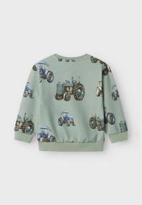 Felpa verde con motivi di trattori, realizzata in materiale morbido. Presenta maniche lunghe e polsini e orlo a coste. Vestibilità comoda.