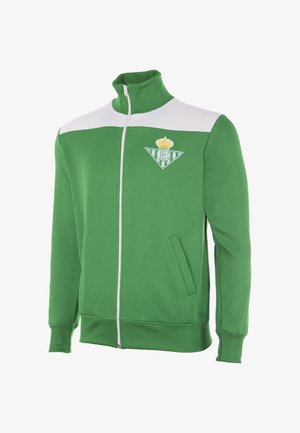 Groene sportjas met rits, wit bovenpaneel op de borst en Real Betis clublogo op de linkerborst, met zijzakken en geribbelde manchetten.