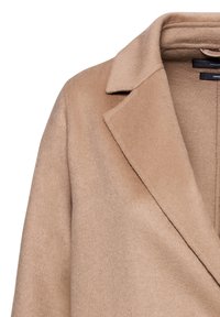 Svetle hnědý kabát z vlněné směsi s klopovým límcem, jemnou texturou a dvouřadým zapínáním. Čisté linie a minimální kovové doplňky.