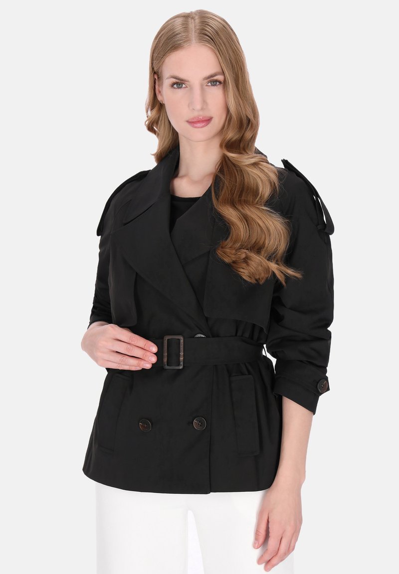 Fekete esőkabát dupla soros gombokkal, széles hajtókákkal és övvel. Felhajtott ujjakkal és oldalzsebekkel rendelkezik. Simább, texturált anyagból készült.