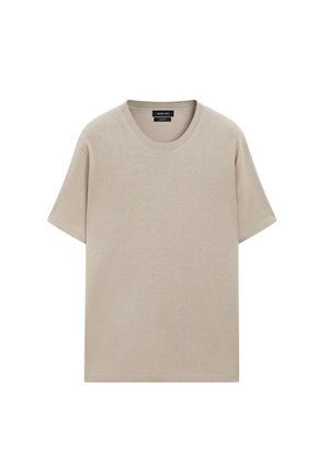 T-shirt en coton beige avec un col rond, des manches courtes et une coupe décontractée. Texture lisse avec un design uni, sans motifs ni accents visibles.