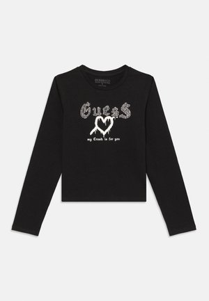 Black long-sleeve cropped shirt with white Gothic-style "Guess" text, a dripping heart graphic, and "my Crush is for you" printed below.