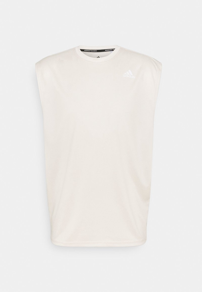 Jasno beżowy bezrękawnik sportowy wykonany z gładkiego materiału. Posiada okrągły dekolt oraz małe białe logo na górnej lewej części klatki piersiowej.