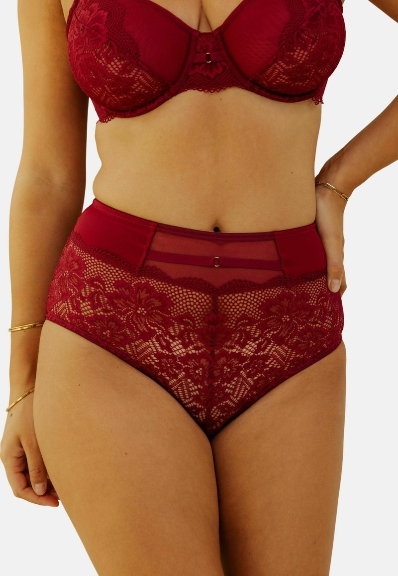 Ensemble comprenant un soutien-gorge en dentelle bourgogne et une culotte taille haute, ornés de motifs floraux, de panneaux transparents et de délicates accents en doré. Texture lisse.