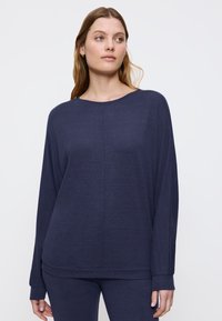 Top lungo a maniche con un blu navy, dal taglio morbido, scollato ampio e polsini a costine, realizzato in un tessuto leggero e texturizzato.