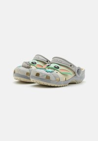 Lightweight grey clogs featuring a green cartoon character face, with ventilation holes, textured sole, and adjustable heel strap.