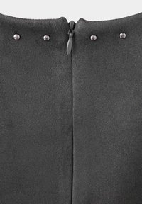 Gros plan d’un tissu gris foncé avec une fermeture éclair noire centrée et quatre rivets métalliques espacés uniformément près du bord supérieur.
