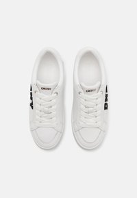 Sneakers bianchi realizzati in materiale sintetico liscio. Presentano un logo nero, punta rotonda, lacci piatti e colletto imbottito per il comfort.