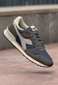 Scarpa da corsa da uomo caratterizzata da una combinazione di mesh blu navy e suede grigio, con dettagli in pelle beige. Design classico con allacciatura e suola in gomma nera.