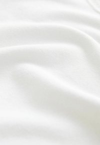 Tissu blanc avec une texture lisse, présentant des plis doux et délicats et une surface légèrement réfléchissante, créant des ombres subtiles.