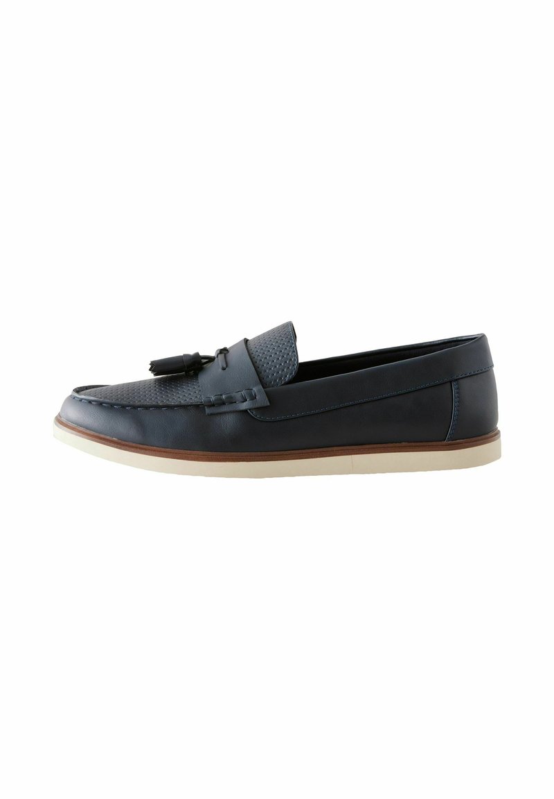 Mocasines de cuero azul marino con punta texturizada, un borlas decorativa y suela crema en contraste. Presenta costuras decorativas y un acabado suave.