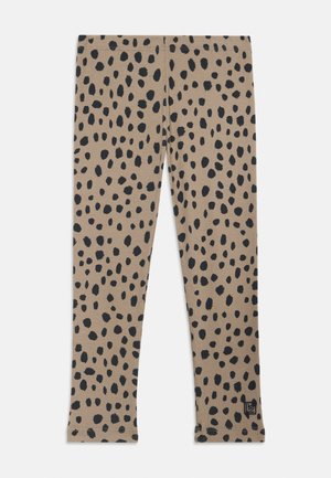 Beżowe legginsy z rozproszonym czarnym wzorem w kropki, wykonane z miękkiego materiału, z dopasowanym krojem i elastycznym pasem.