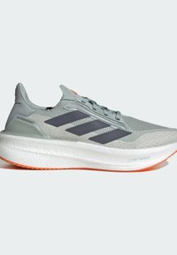 Zapatilla de running Adidas Ultraboost gris claro con parte superior de malla texturizada, rayas gris oscuro y una suela intermedia blanca con acentos naranjas.