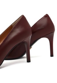 Chaussures à talons hauts en cuir bordeaux avec une finition lisse, un bout pointu et un talon aiguille élancé. Présente un design de décolleté basse.