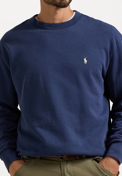 Sweatshirt azul marinho feito de algodão, com gola redonda, punhos canelados e um pequeno logotipo bordado em branco no lado esquerdo do peito.