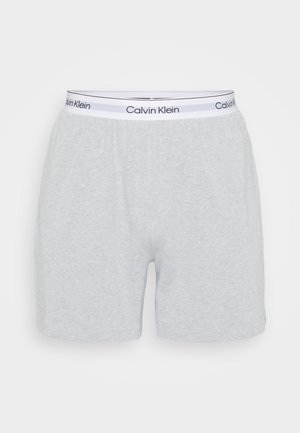 Graue Baumwoll-Boxershorts mit einem elastischen Bund, der ein weißes Band mit der Aufschrift "Calvin Klein" in Schwarz trägt. Glatte Textur, lässige Passform.