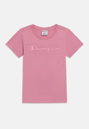 Roze katoenen T-shirt met korte mouwen, met een gestikte "Champion"-logo in een iets lichtere roze tint over de borst.