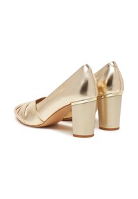 Kuldsed metallik kõrge kontsaga kingad ümmarguse varbaga ja lõigatud detailidega. Paks plokknakk ja kuldne aktsent aluses. Siledad tekstuurid.