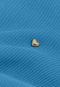 Blauwe ribstof met een klein gouden hartvormig versierding, met een gestructureerd oppervlak en een gekettelde rand rond het hart.