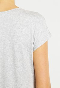 Lichtgrijze T-shirt met korte mouwen en een ronde halslijn. Zachte stof, licht gemêleerd patroon, ontspannen pasvorm met opgerolde mouwuiteinden.