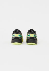 Svart og grå atletiske sko med neongule detaljer og grønne merker. Har en teksturert overdel og gummisåle for godt grep.