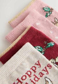 Four pairs of socks in pink, red, and cream. Textured knit, featuring holiday patterns and gold-accented cuffs.