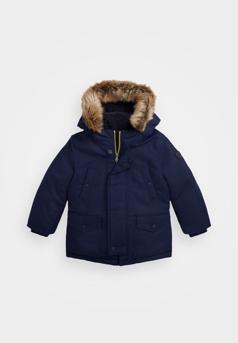 Parka bleu marine avec capuche doublée de fausse fourrure, fermeture éclair, deux poches avant et poignets côtelés, conçue pour la chaleur et le confort.