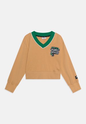 Sweatshirt court à manches longues en beige avec un col en V vert, présentant un patch logo "Fila" sur la poitrine et un détail de poignet de marque.