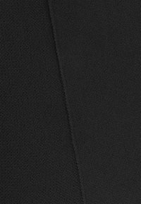 Zwarte gebreide stof textuur toont een consistente nerf. De stof heeft een zachte, gladde uitstraling met een lichte elasticiteit en geen zichtbare patronen.