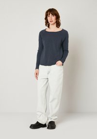 Jūrinis ilgos rankovės viršus, laisvas kirpimas, apvalus iškirpimas; derinamas su šviesiai mėlynomis baggy džinsomis ir juodais neslystančiais batais. Sklandus, audinio tekstūra.