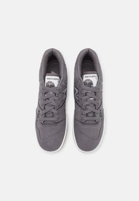 Šedé plátěné tenisky s šněrovacím designem, obsahující texturovaný svršek, gumovou podešev a značení "New Balance 550" na jazyku.