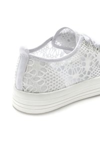 White sneaker featuring a mesh upper with a lace-up design, soft fabric detailing, and a textured rubber sole with three horizontal stripes.