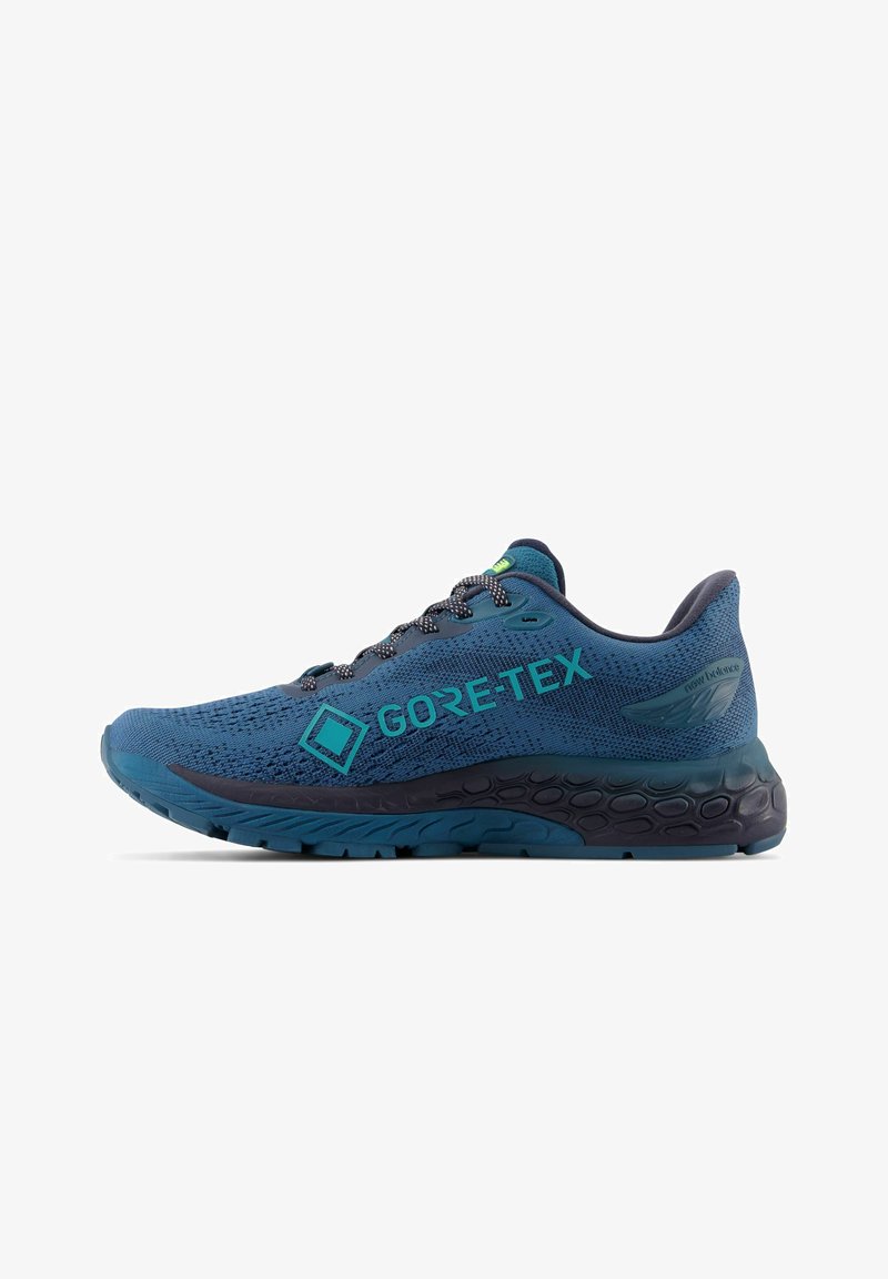 Blauer Laufschuh mit GORE-TEX-Branding. Verfügt über ein strukturiertes Mesh-Obermaterial, eine kontrastierende dunkle Sohle und reflektierende Akzente an den Schnürsenkeln.