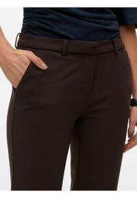 Rjave hlače po meri z gladko teksturo, z bočnimi žepi in ravnim pasom. Tkanina ima rahlo sijaj.