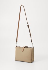 Bež sintetička crossbody torba pravokutnog oblika, smešani podesivi remen, srebrni metalni detalji i zatvaranje na zip. Jednostavna tekstura s minimalnim akcentima.