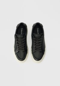 Fekete bőr sportcipők fehér gumitalppal, kerek orral és fűzős kialakítással. Tartalmazza a márkajegyzést a talpbetéteken és sima textúrájú.