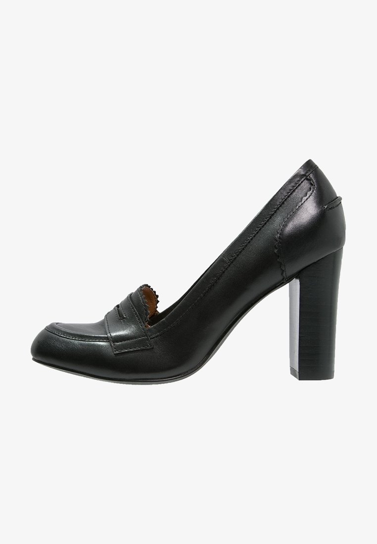 Chaussure à talon haut en cuir noir avec bout rond, détails subtils cousus et talon bloc texturé. Conçue de manière classique avec un accent mocassin.