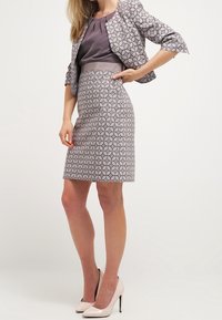 Grijze gestreepte pakkenrok met een aansluitende, gestreepte blazer en een effen top. De outfit heeft een glanzende textuur en wordt aangevuld met naaldhakken in een nude kleur.