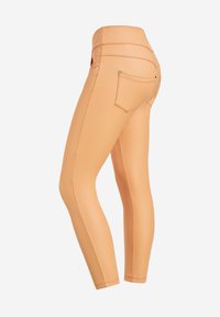 Leggings elasticizzati color carne con vita alta, dotati di tasche posteriori e cuciture a contrasto, progettati per modellare il corpo.